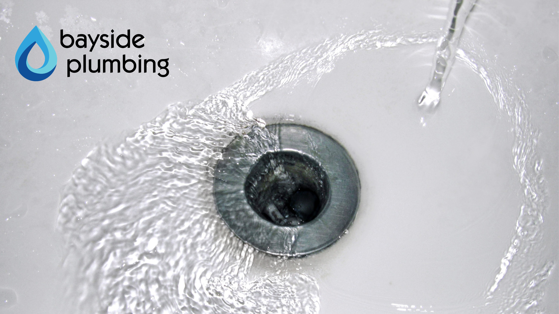 Clear water swirling rapidly and draining smoothly down a clean porcelain sink drain.