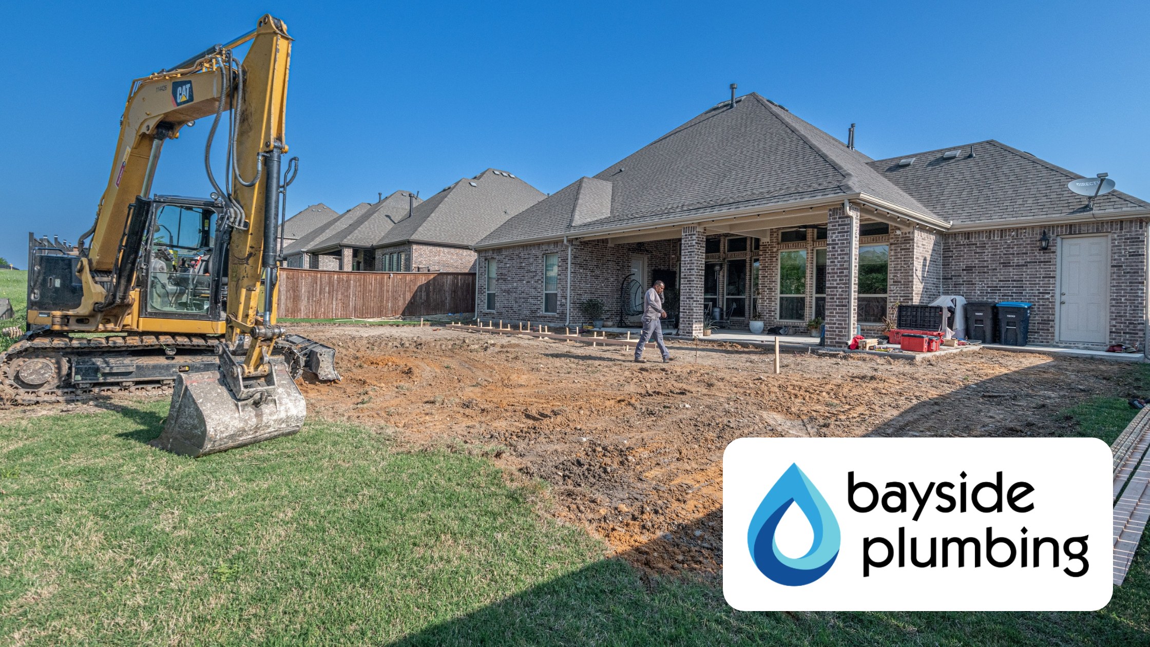 Excavator digging in the backyard of a Baldwin County home during grinder pump installation