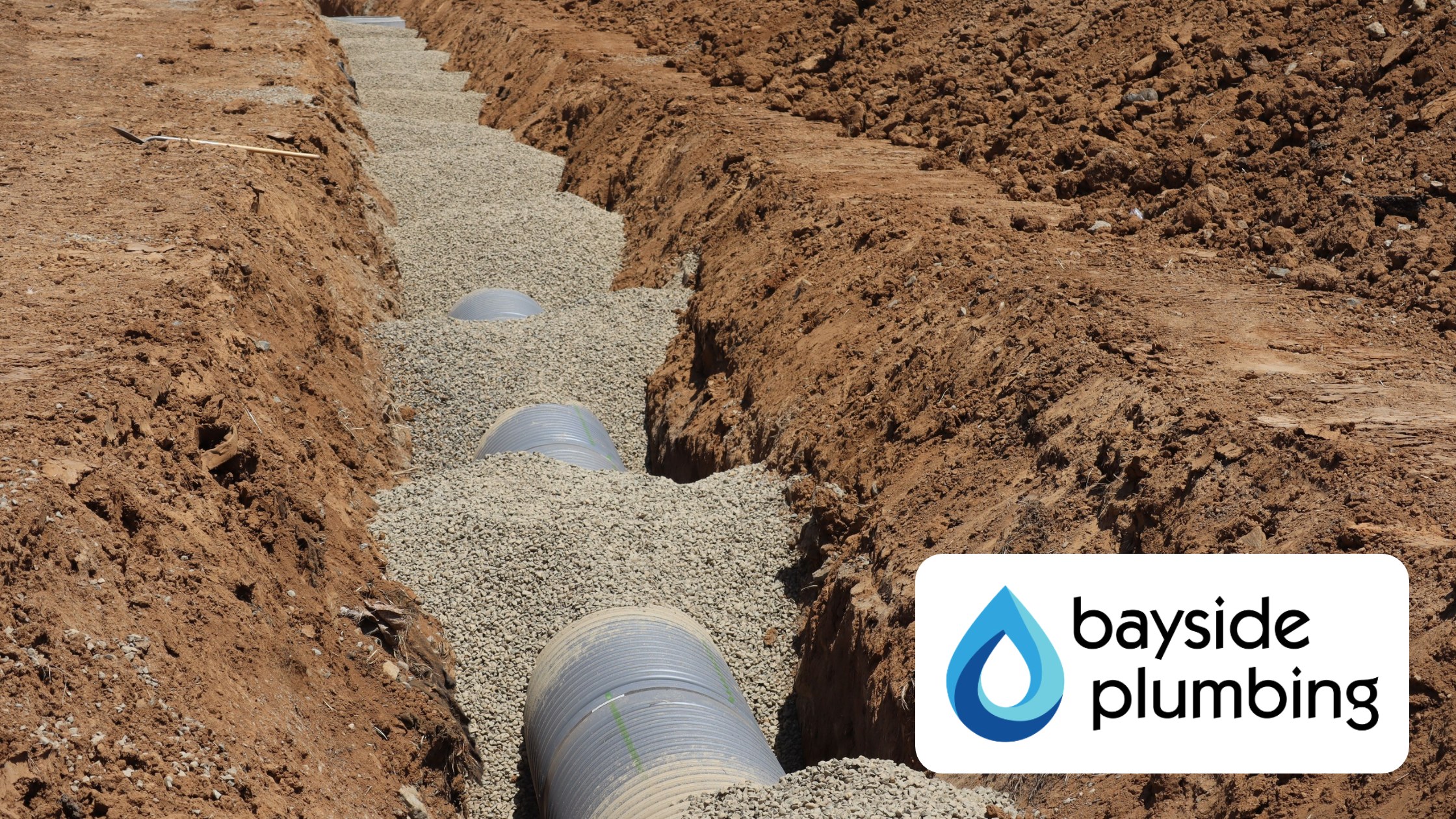 New sewer line pipe bedded in gravel inside an open trench during a Baldwin County sewer repair